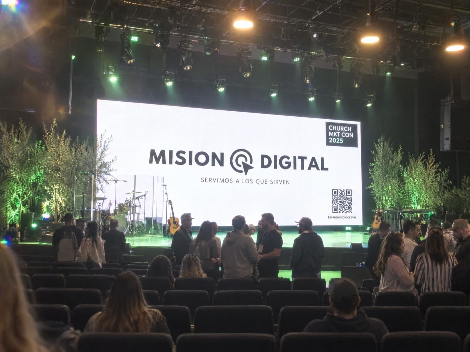 El logo de Misión Digital en la pantalla principal de una conferencia, frente al público.